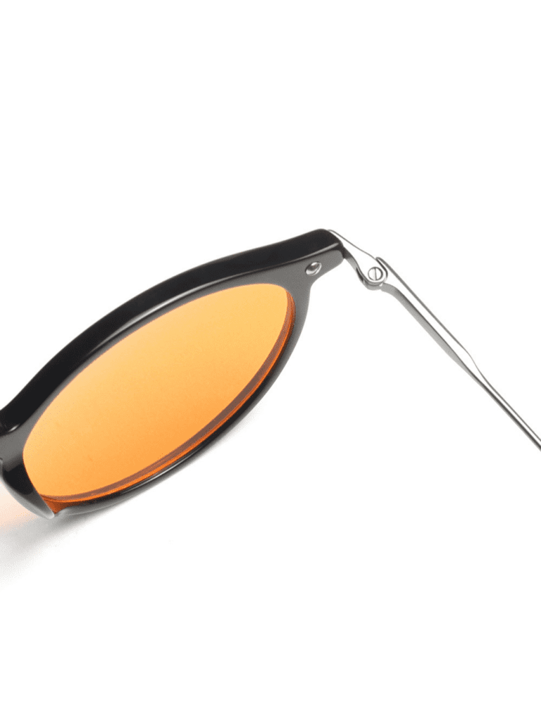 Nahaufnahme einer schwarzen Retro-Sonnenbrille mit orangefarbenem Glas und schmalem silberfarbenem Bügel