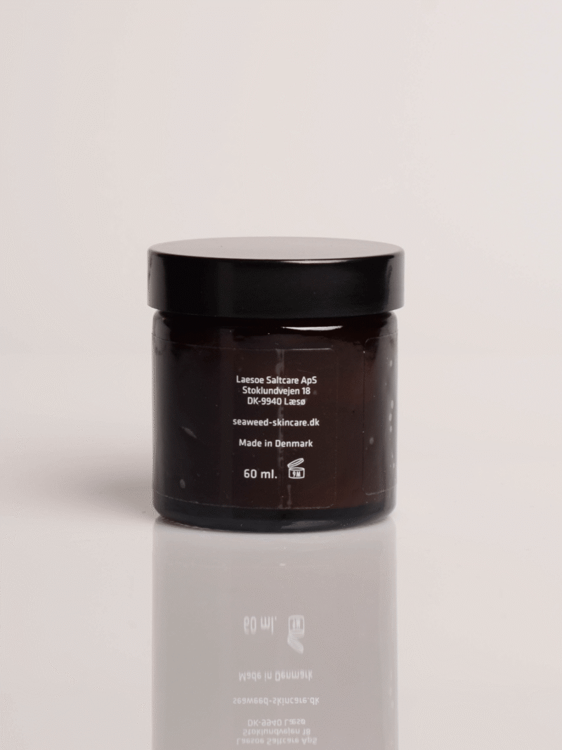Brauner Glastiegel mit schwarzem Deckel, Pflegecreme 60 ml mit Algenextrakt, gespiegelt auf glänzender Oberfläche