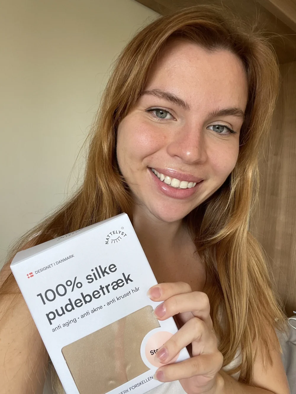 Lächelnde Frau hält die Verpackung eines Seidenkissenbezugs aus 100 % Seide
