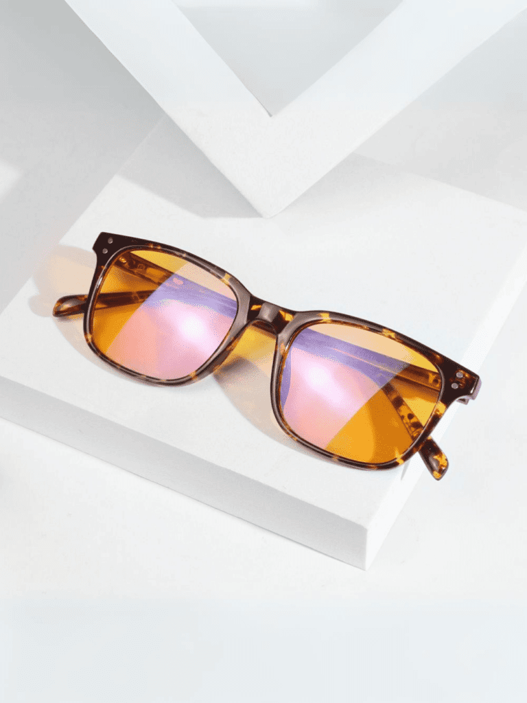 Brun tortoise-solbrille med orange-rosa spejlglas og firkantet stel på hvide geometriske blokke