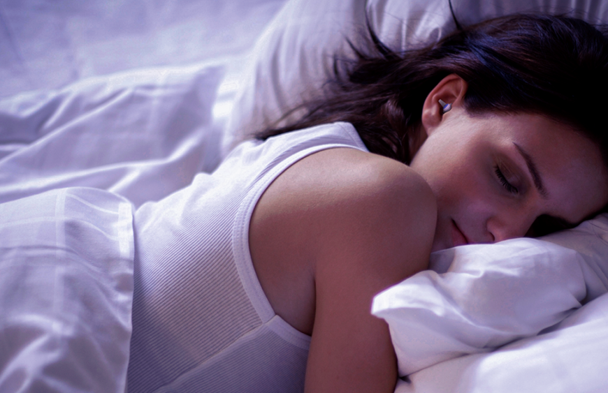 Frau schläft im Bett mit SleepDeep Ohrstöpseln neben einem schnarchenden Partner