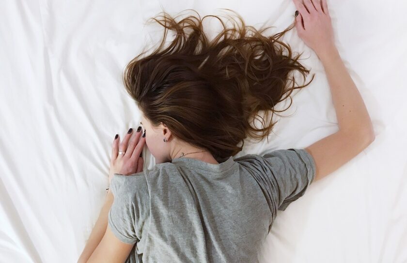 Junge Frau liegt unruhig im Bett und kämpft mit Schlafmangel