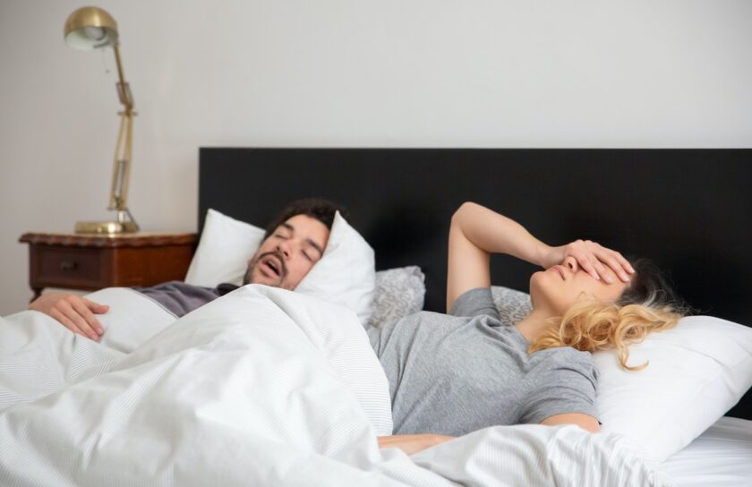 Ein Mann und eine Frau im Bett. Die Frau kann nicht schlafen, weil der Mann schnarcht