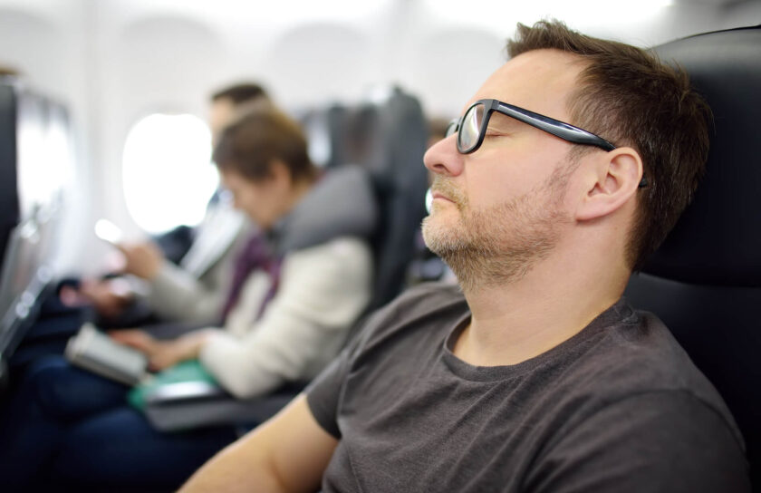 Mann schläft entspannt im Flugzeug