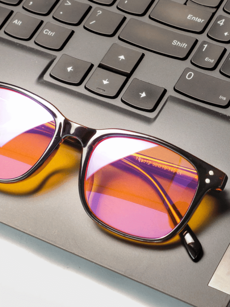 Sonnenbrille mit pink-orange verspiegelten Gläsern auf einer Laptop-Tastatur neben den Pfeiltasten