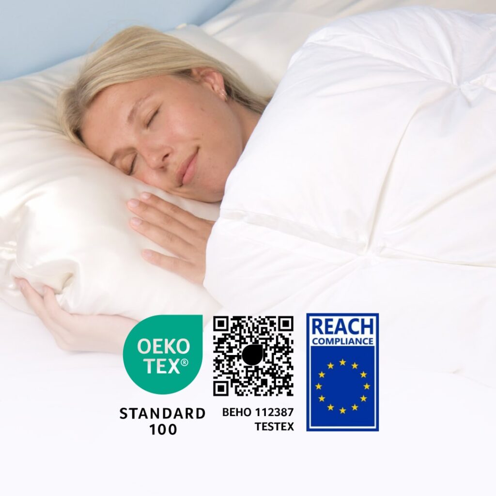 Kvinde sover trygt under hvid hybriddyne med OEKO-TEX Standard 100 og REACH-certificeringsmærker