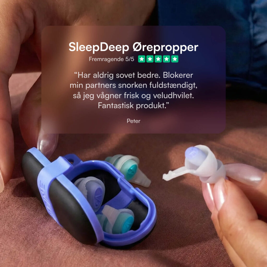 SleepDeep ørepropper i lilla etui på sengetøj, hånd holder blød silikone ørepropper til støjreduktion og bedre søvn.